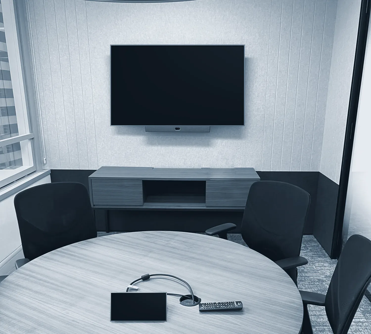 A meeting room with a wall screen, camera bar and room tablet