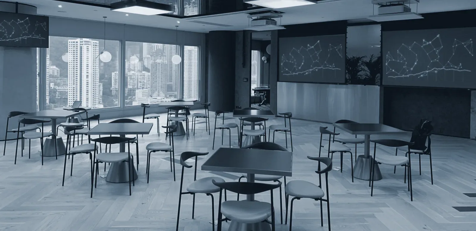 An office lounge with projection screens and a wall screen, overlooking the city