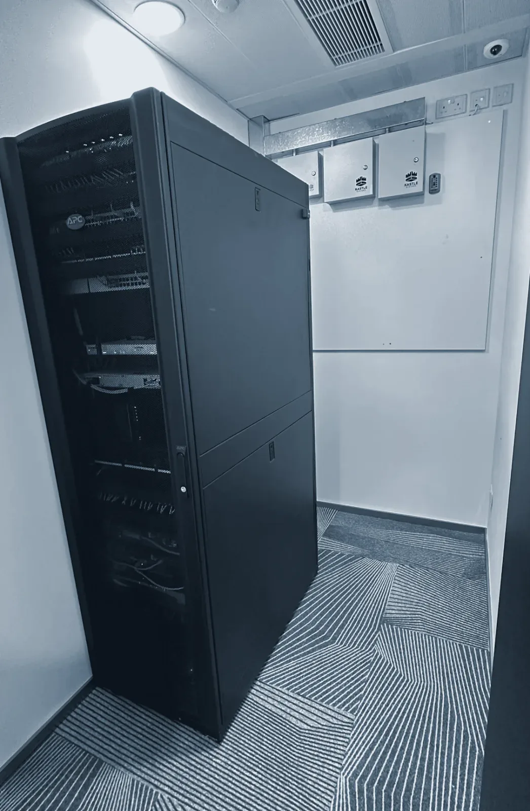A comms room with a locked server cabinet and access control on the wall