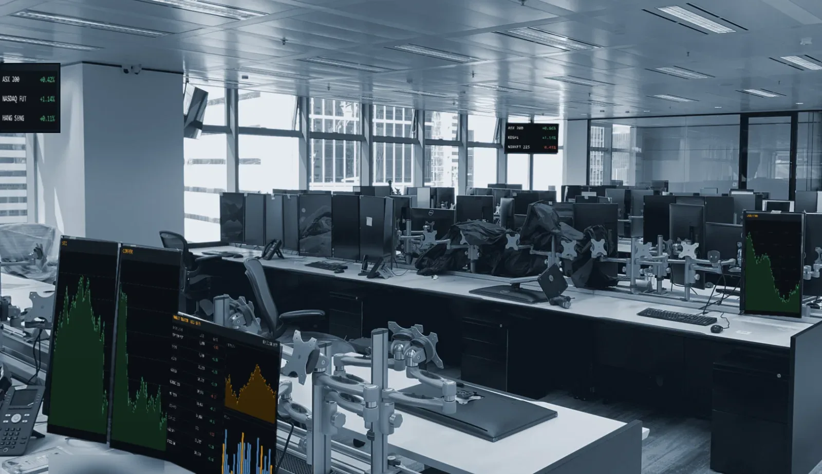 A trading floor with rows of desks, multi-screen monitor arms and desk phones
